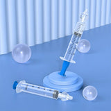 Two syringes on a blue surface with a light blue curtain background