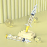 Two syringes with a yellow liquid on a light green surface with a striped background