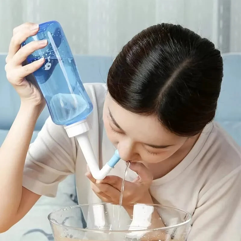 Person using a nasal cleaning device with a clear bowl below.