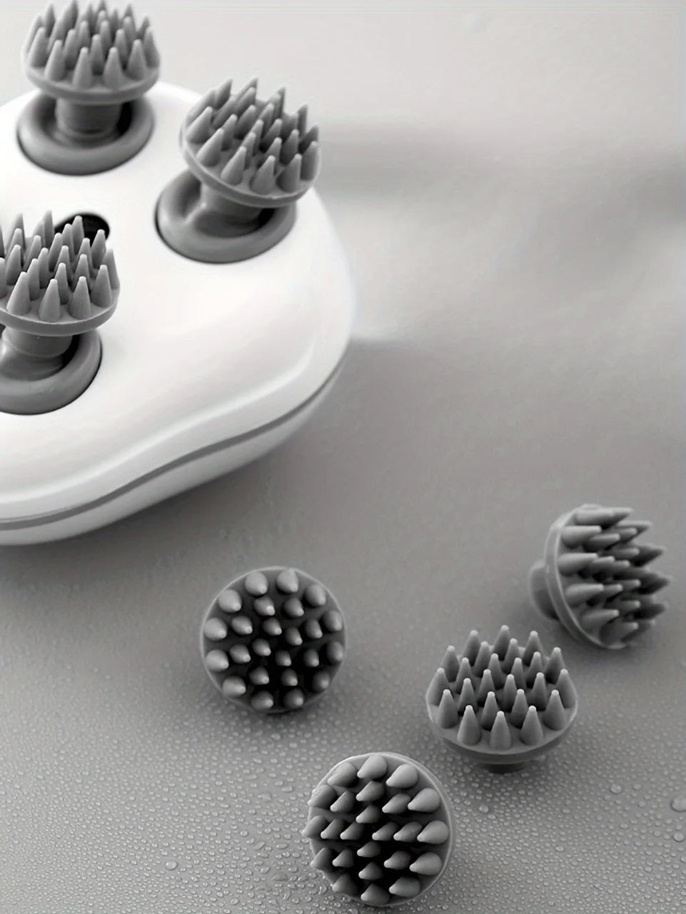 Gray silicone scrubber heads on a white base with additional scrubber heads scattered on a gray surface.